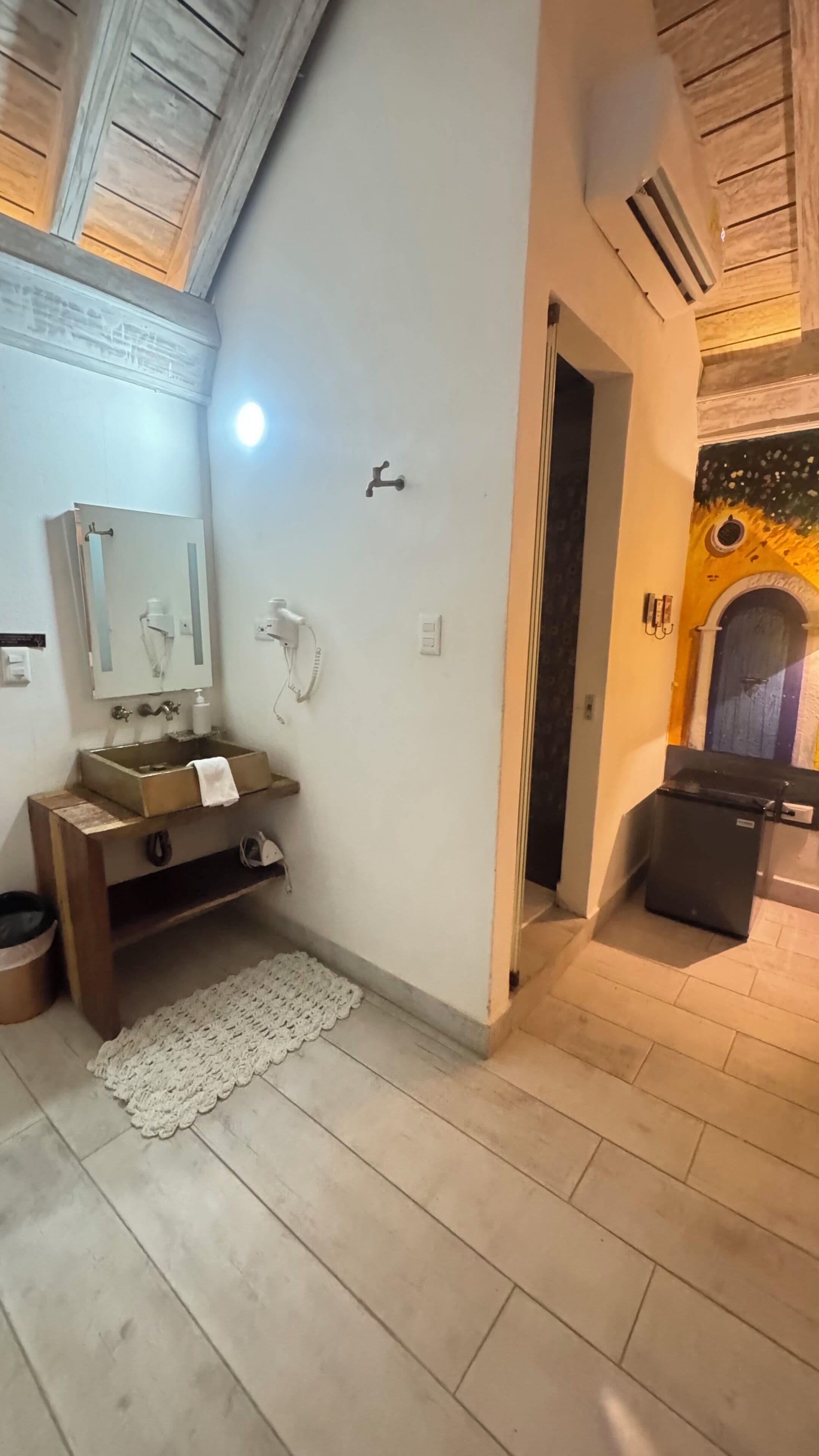 A bathroom with a wooden vanity, a sink, a mirror, and a towel rack.