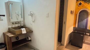 A bathroom with a wooden vanity, a sink, a mirror, and a towel rack.