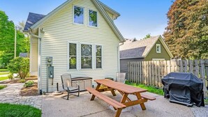 Een huis met een picknicktafel en stoelen in de achtertuin.