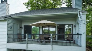 Een huis met twee verdiepingen, met een balkon op de bovenverdieping, voorzien van stoelen en een parasol.