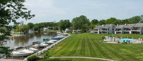 A marina with boats docked, a well-maintained lawn, and residential buildings in the background.