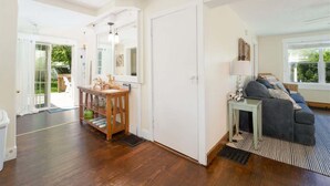 A spacious living room with a dark wood floor, a grey sofa, and a striped rug. - Beach Grass, 2 BR, South Haven, Walk to the Beach (South Haven)