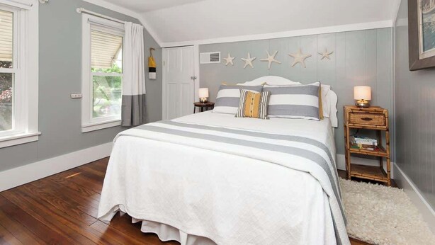 A bedroom with a large bed, a bedside table, a nightstand, and a wall-mounted star decoration. - Isabel • walk to beach & downtown South Haven (South Haven)
