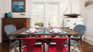 A dining area with a wooden table set for four, surrounded by patterned chairs. - Isabel • walk to beach & downtown South Haven (South Haven)