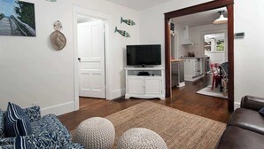 A living room with a TV, a sofa, and a kitchen in the background. - Isabel • walk to beach & downtown South Haven (South Haven)
