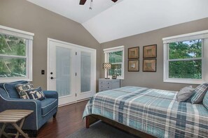 A bedroom with a bed, a blue sofa, a dresser, and framed pictures on the wall.