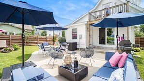 A backyard patio with outdoor furniture, umbrellas, and a grill. - SH Cottage (South Haven)
