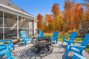 A patio area with a fire pit and blue Adirondack chairs.