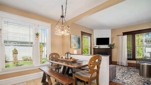 Un espace repas avec une table et des bancs en bois, un luminaire suspendu et une cheminée.