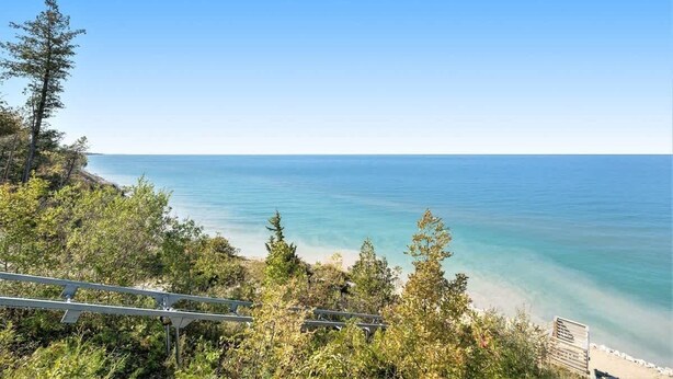 Une vue sur la côte, avec un ciel dégagé, une plage et une zone boisée comprenant une structure en bois.