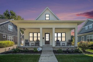 Une maison à deux étages avec un porche à l’avant, un petit jardin devant et une boîte aux lettres.