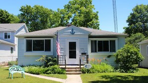 A two-story house with a front porch, a mailbox, and a small garden with a bench. - Mail Legacy Cottage in South Haven • Dogs Welcome (South Haven)