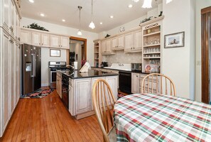Modern kitchen with central island, refrigerator, stove, and dishwasher, featuring a dining table and seating area.