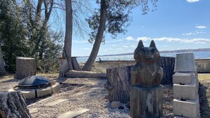 Un espace extérieur paisible agrémenté d’une sculpture en pierre, d’un foyer et offrant une vue sur un lac.