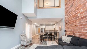 A modern living room with a grey sofa, a patterned armchair, and a dining area with a table and chairs.