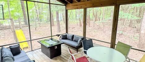 Un espacio de estar al aire libre cubierto con sofá, sillas, una mesa y un brasero.