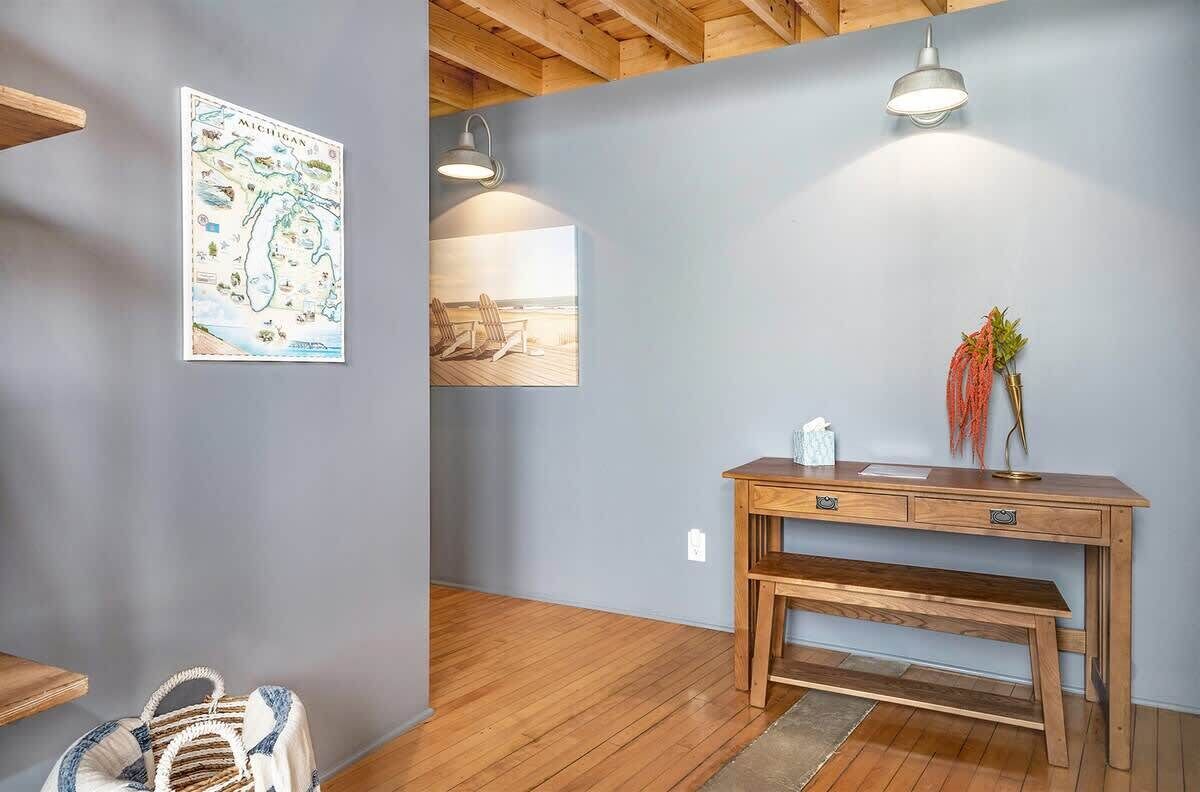 A room with a wooden desk, a bench, a map of Michigan, and two pendant lights.