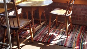 A room with a wooden table and chairs, a colorful rug, and large windows with a view of a body of water.
