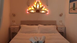 A hotel room with a bed, a headboard with lights, two bedside tables, and a wall-mounted picture. - Antica Dimora Giusy Ostuni (Ostuni)