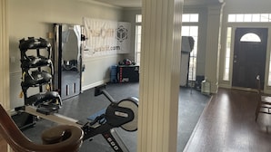 A home gym with exercise equipment, a banner, and a large window. - Home in South Tulsa (Tulsa)