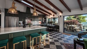 Una cucina moderna con una grande isola, sgabelli da bar e luci a sospensione.
