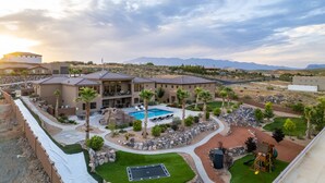 A resort with a swimming pool, outdoor seating, and a view of mountains. - Large 9 Bedroom Home w/Private Pool, Indoor Sports Court & Arcade Room (Hurricane)