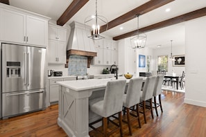 A modern kitchen with white cabinetry, stainless steel appliances, and a large island with bar stools.