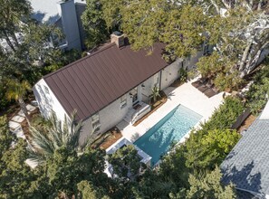 Vue aérienne d’une maison avec piscine, entourée d’arbres et d’un jardin bien entretenu.