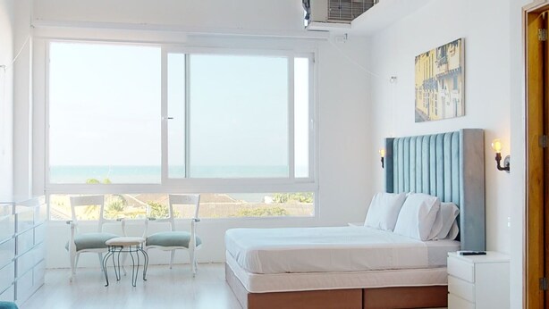 Una camera da letto con una grande finestra, un letto, un comodino e una sedia.