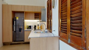 Cucina compatta con mobili in legno, frigorifero in acciaio inossidabile, forno a microonde e lavello.