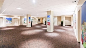 A spacious hotel lobby with a high ceiling, multiple columns, and artwork on the walls.