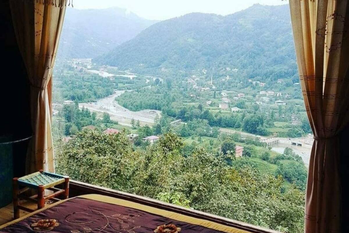 A room with a view of a valley and mountains.