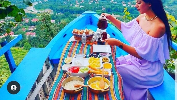 A person enjoying a meal on a blue boat with a scenic view of a valley and mountains in the background. - Olimbera Köy Evi (Arhavi)