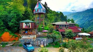 A traditional house with a tower, surrounded by lush greenery and mountains. - Olimbera Köy Evi (Arhavi)