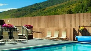 Una piscina con sillas de descanso y una valla de madera.
