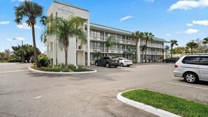 A multi-story hotel with a central entrance, parking area, and palm trees. - Wonderful Apt Hotel with Pool in Kissimmee 3 (Kissimmee)