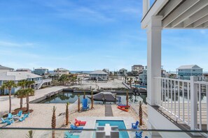 A beachfront property with a pool, beach chairs, and a dock.