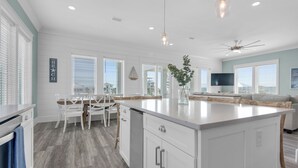 A spacious kitchen with white cabinetry, a central island, and a dining area with white chairs. - Blue Chair | 🚤 Boater’s Paradise | Pool | Dock | Outdoor Bar | Pet Friendly 🐾 (Navarre)