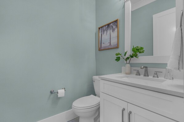 A bathroom with a toilet, sink, and mirror.