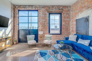 Un salon spacieux avec une grande fenêtre, un canapé bleu et une table basse.
