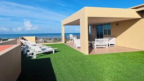 A rooftop terrace with artificial grass, white lounge chairs, and a view of the ocean. - Unique and Private Panoramic Ocean View Penthouse in Cabo Rojo, Puerto Rico (Cabo Rojo)