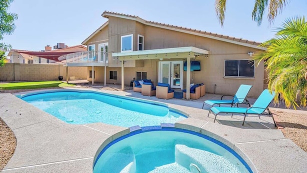 A two-story house with a swimming pool, outdoor seating, and a covered patio area.