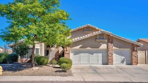 A single-story house with a brick facade, a garage, and a tree in the front yard.