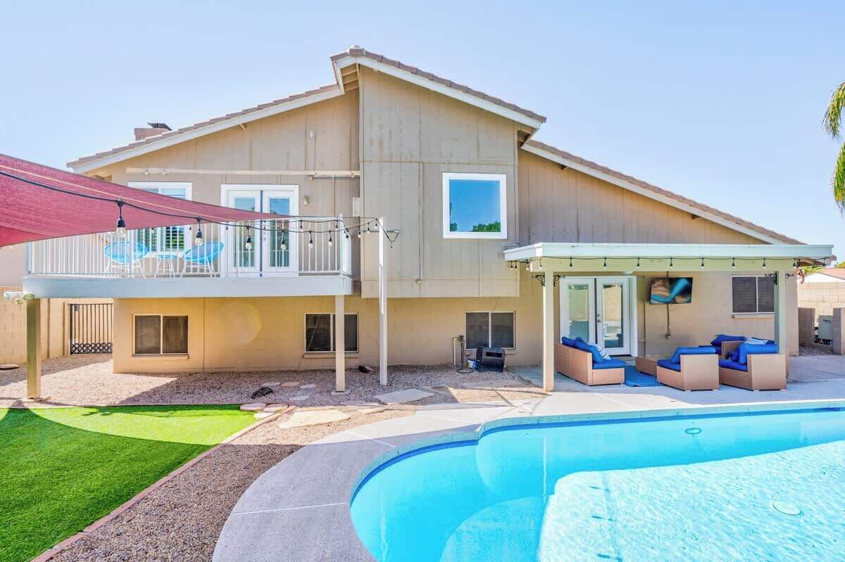 A two-story house with a swimming pool, a covered patio, and a fenced backyard.
