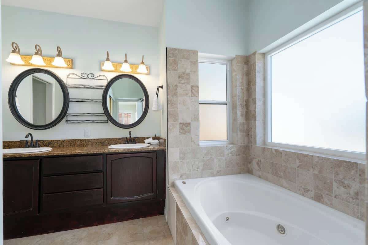 A bathroom with two sinks, a large mirror, and a bathtub.