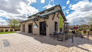 En byggnad med en täckt uteplats, utomhusmöbler och en inhägnad parkeringsplats.