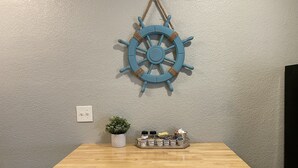 A wooden table with a ship's wheel decoration and a small potted plant on a textured wall. - Anchors UP #1; WALK to Beach/Bars/Dining (Clearwater)