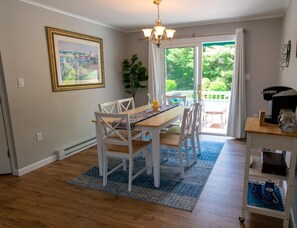 Enjoy meals in this inviting dining area with a large window offering a view of lush greenery.