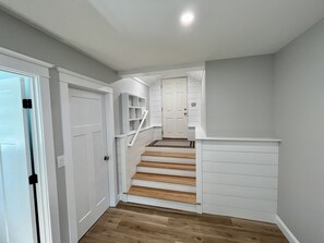 A staircase with wooden steps and white railings, leading to a landing with a door.