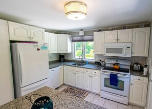 A kitchen with white cabinets, a refrigerator, a microwave, an oven, and a sink.